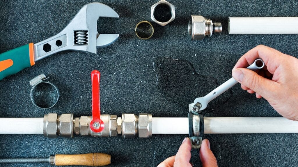 Plumber repairing a pipe valve with an adjustable wrench in Redmond