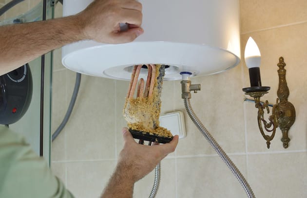 Technician removing mineral buildup from a water heater in Redmond