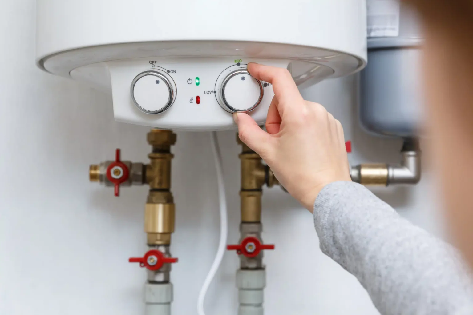 Homeowner adjusting the temperature controls on a water heater in Redmond